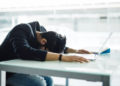 Stock image of a man with his face on a desk. Gen Z-ers are getting fired, and one expert told Newsweek it may not be their fault. dangrytsku/Getty Images