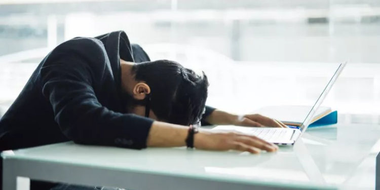 Stock image of a man with his face on a desk. Gen Z-ers are getting fired, and one expert told Newsweek it may not be their fault. dangrytsku/Getty Images