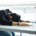 Stock image of a man with his face on a desk. Gen Z-ers are getting fired, and one expert told Newsweek it may not be their fault. dangrytsku/Getty Images