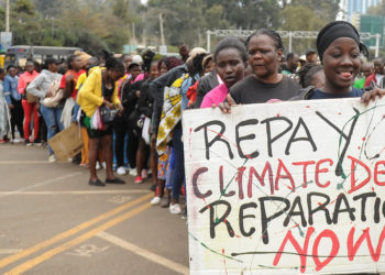 A member of the civil society holds a placard as others queue during a peaceful protest against the continent's inaugural climate summit, marching against the use of fossil fuels in the region while demanding that governments and industries transition to renewable energy in Nairobi, Kenya September 4, 2023. REUTERS/John Muchucha