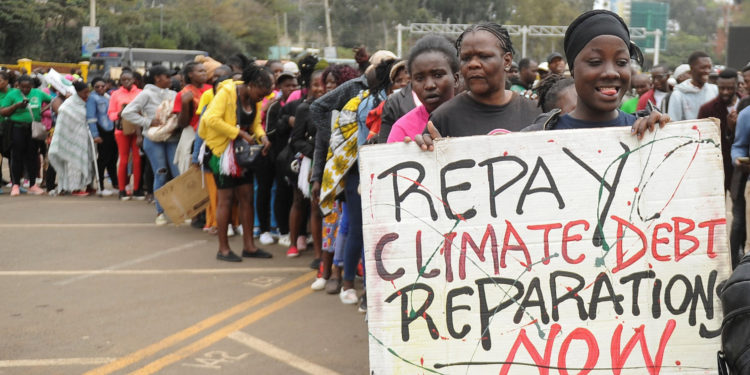 A member of the civil society holds a placard as others queue during a peaceful protest against the continent's inaugural climate summit, marching against the use of fossil fuels in the region while demanding that governments and industries transition to renewable energy in Nairobi, Kenya September 4, 2023. REUTERS/John Muchucha